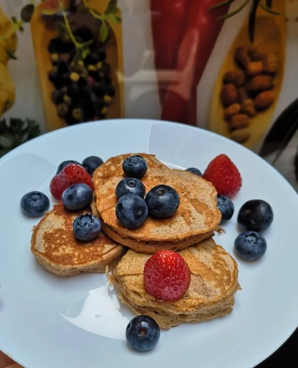 Zdrowy i zbilansowany posiłek: wegetariańskie kotleciki z marchewką, pomidorkami i świeżą kolendrą na białym talerzu.